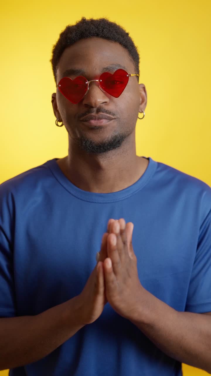Man with heart-shaped sunglasses in front of a yellow background