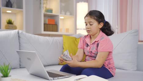 Girl-child-looking-at-laptop-counting-money.