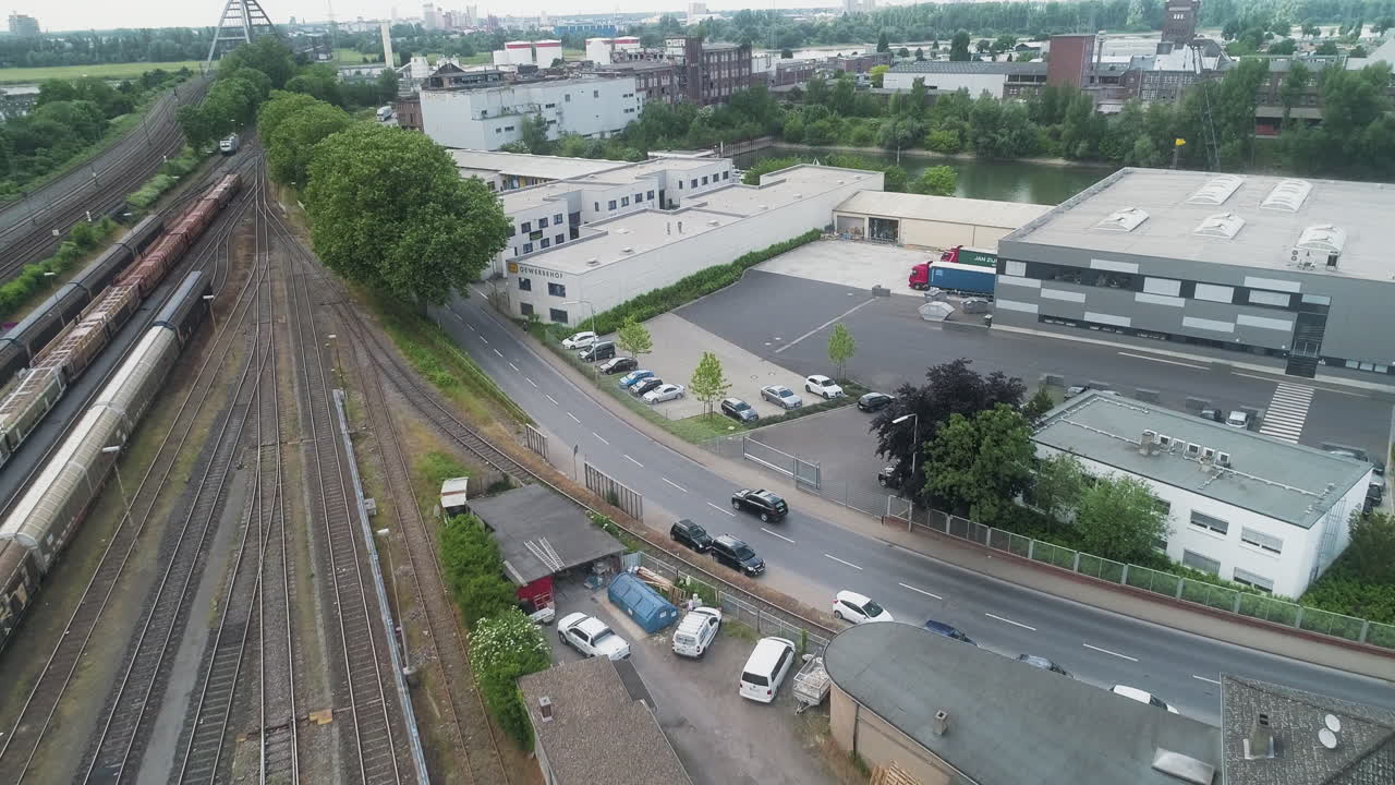 Drone følger bil som kjører langs jernbanespor i et industrielt urbant område i Tyskland