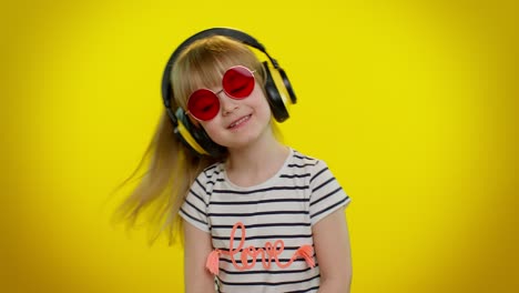 Funny-playful-blonde-kid-child-girl-listening-music-via-headphones,-dancing-disco-fooling-having-fun