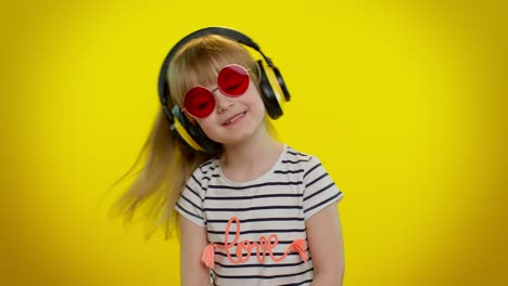funny playful blonde kid child girl listening music via headphones, dancing disco fooling having fun