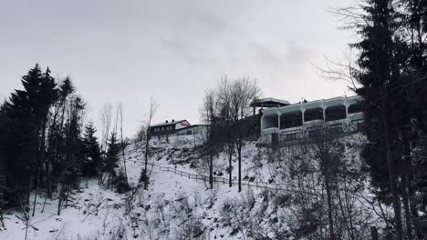 Small-path-with-wooden-railing-leads-up-a-snowy-mountain-with-small-snowy-houses-in-the-background