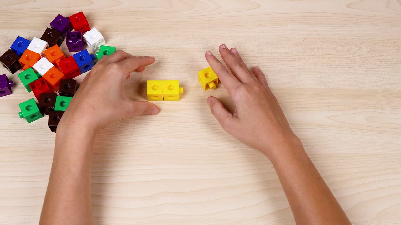 manos montando cubos amarillos en una mesa de madera