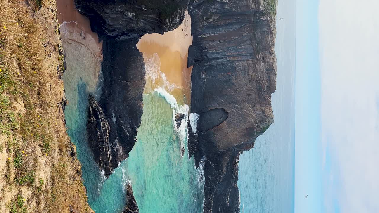 zambujeira do mar sobre la orilla del mar con olas del océano, acantilados y dunas de arena cubiertas de vegetación verde hojas rojas de higo agrio, día soleado, cielo azul claro