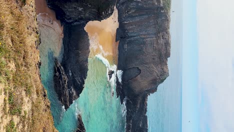 zambujeira do mar over the sea shore with ocean waves, cliffs and sand dunes covered by green vegetation red leaves of sour fig, sunny day, clear blue sky