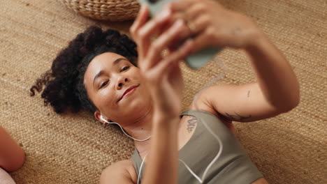 mujer relajándose en casa con teléfono y auriculares
