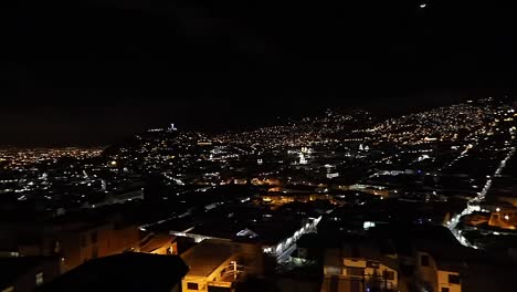 vista panorámica nocturna de quito, ecuador, con luces de la ciudad, luna y estatua de la virgen del panecillo