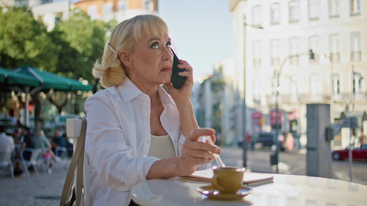 노인 사업가 여성이 오픈 카페에서 스마트폰 커뮤니케이션에 불만을 품고 있습니다.