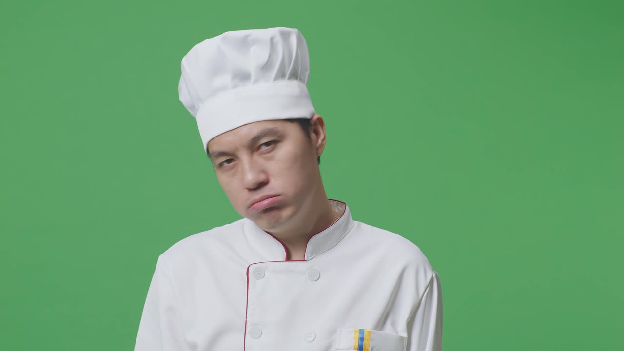 primer plano de un chef asiático con dolor de cabeza mientras está de pie en el estudio de fondo de la pantalla verde