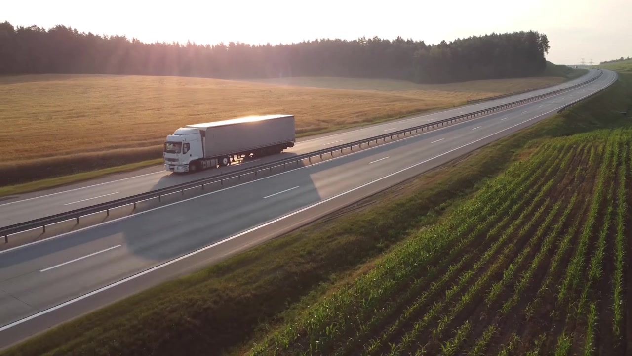 Semi camion che guidano sull'autostrada al tramonto