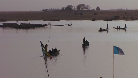 men row boats in silhouette on a river in mali