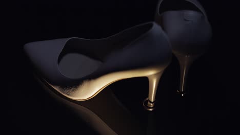 beautiful women cream-colored evening shoes lie on the floor with two golden wedding rings close-up