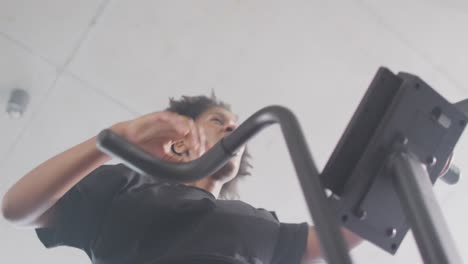 low angle video of tired african american woman on exercise bike working out at a gym