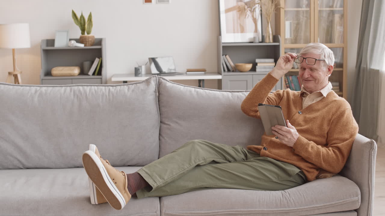 Senior Man Relaxing on Sofa with Digital Tablet