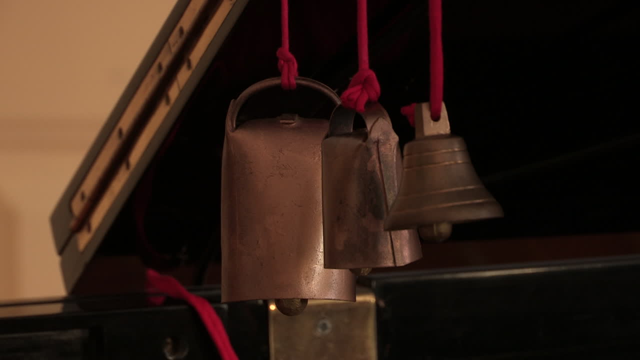 Primo piano di sonagli e una piccola campanella, appesi a un filo rosso.