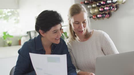 caucasian lesbian couple calculating finances together using laptop at home