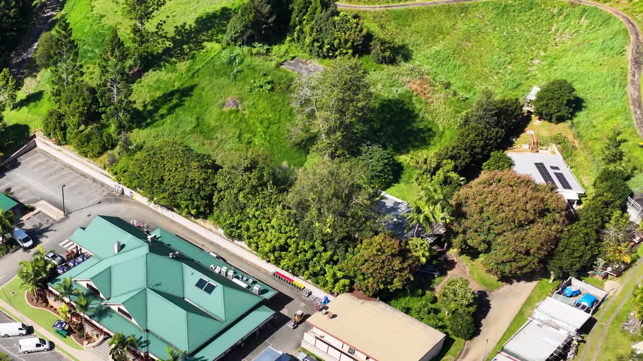 Aerial footage captures a lush green landscape with buildings, showcasing vibrant greenery and architectural structures under bright daylight