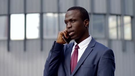 serious black businessman talking on the phone in the city