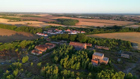 Drone-footage-of-flying-over-an-abandoned-coal-mine,-with-a-village-in-the-background