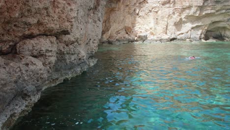 joven atlética buceando en hermosas aguas cristalinas cerca de acantilados rocosos en malta en un día soleado de verano