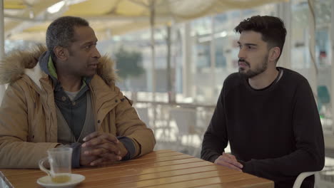 multiethnic men sitting and talking in cafe