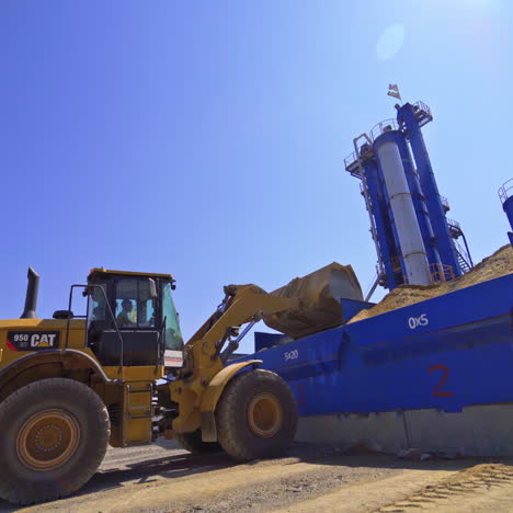 contemporary asphalt factory background. excavator transports asphalt into special tanks outdoors.