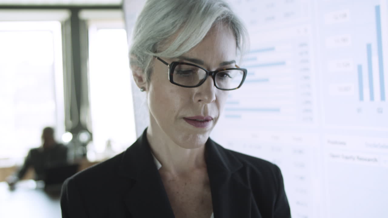 Experienced businesswoman in eyeglasses typing on tablet