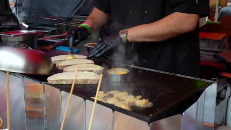 street food chef at work preparing a sandwich applying butter and spices