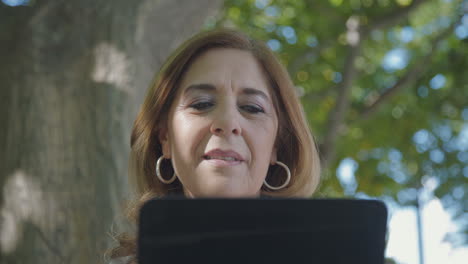 Bottom-view-of-elegant-woman-sitting-outside,-googling-on-tablet