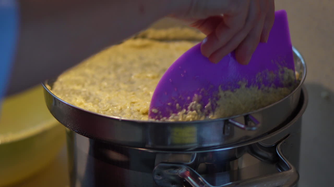 Close Up Of Potato Dough Lumps Dropping Onto Boiling Water In Pot Using Spaetzle Maker. Making Bryndzove Halusky Dumplings