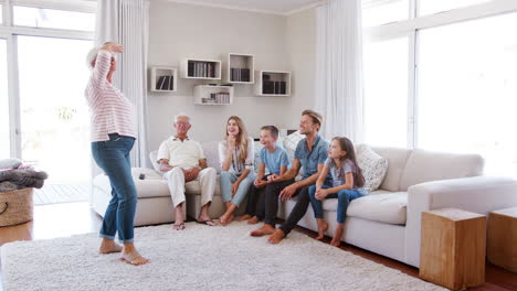 multi generation family sitting on sofa at home playing charades
