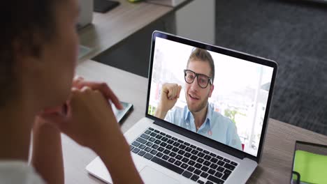 Mid-section-of-african-american-woman-having-a-video-call-on-laptop-with-male-colleague-at-office