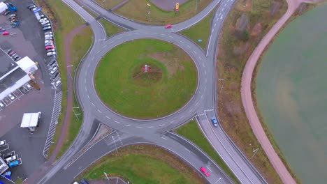 rotating drone footage of a roundabout with with a dalahäst in the middle, on a cloudy day in october