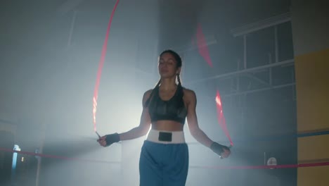 front view of a young caucasian sportswoman with braided pigtails jumping rope in boxing ring