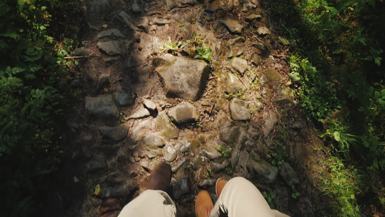 A Couple Of Tourists Are Walking Along A Slippery Stony Path First-Person View Hiking And Active Res