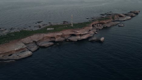 Bandada-De-Gaviotas-Volando-Y-Descansando-En-La-Isla-Rocosa-De-Ile-Pate-Cerca-De-Pointe-Saint-pierre-En-Quebec,-Canadá