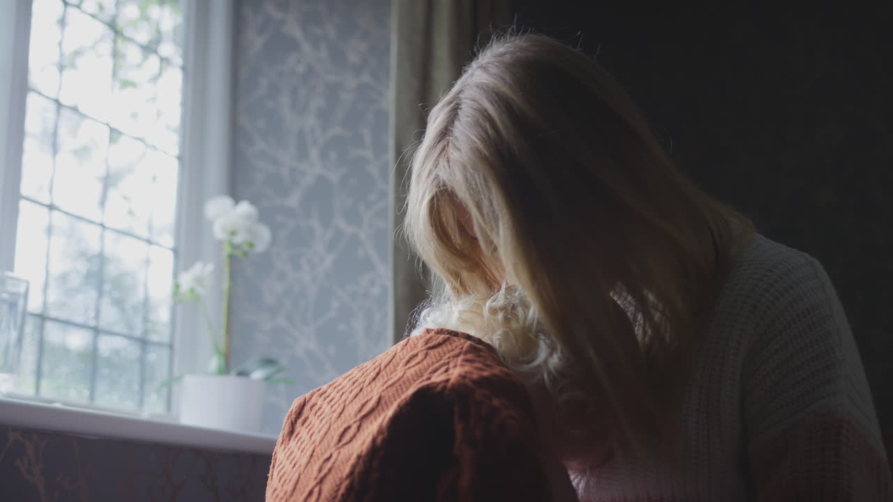 어머니는 아들을 안고 게임을 하고 있습니다. 생활비가 비싼 에너지 위기 중에 집에서 따뜻하게 지내려고 합니다.