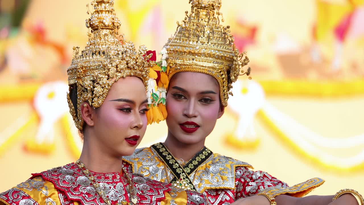 Primo piano di due ballerini thailandesi che eseguono movimenti tradizionali del Khon in elaborati costumi dorati.