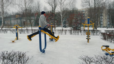 Adult man doing wide steps on the special sport simulator. Practicing sport outdoors in the evening.