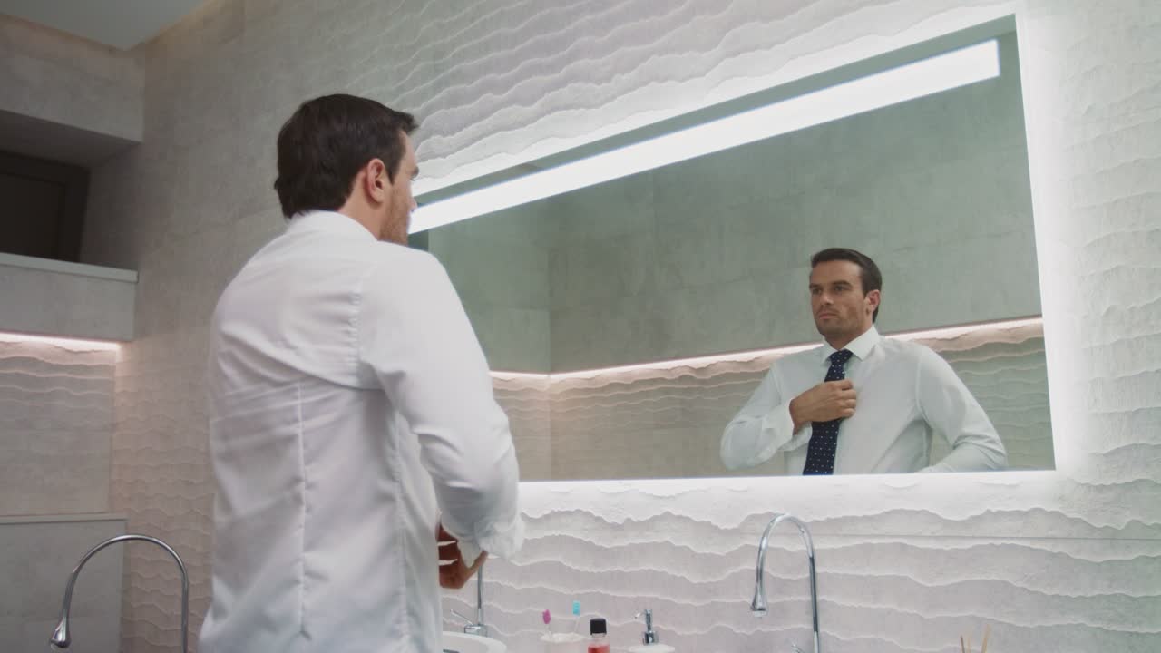 Uomo d'affari che indossa la cravatta in un bagno di lusso. Uomo felice che si veste in casa