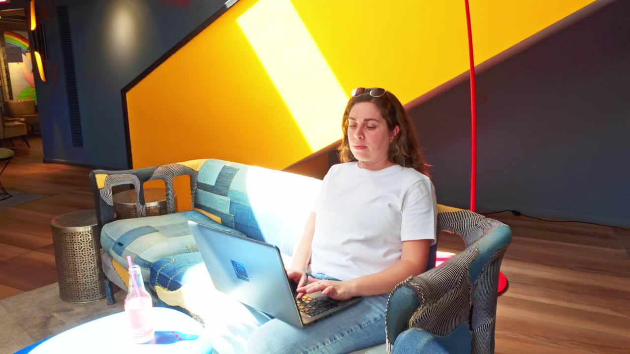 Donna che lavora al laptop in una lounge di coworking creativa
