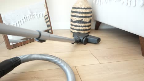 vacuuming a light-colored wooden floor in a modern home