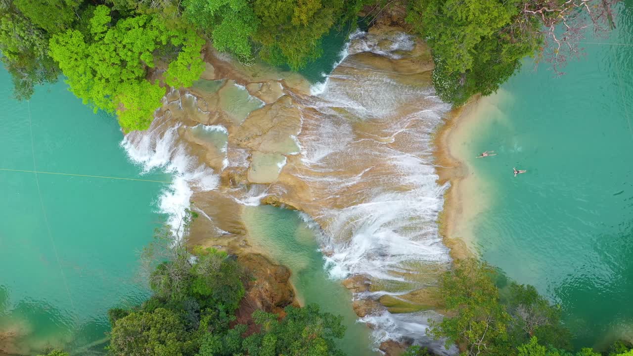 Aerea: viaggiatori che nuotano nelle pozze di cascate tropicali, vista dall'alto in risalita