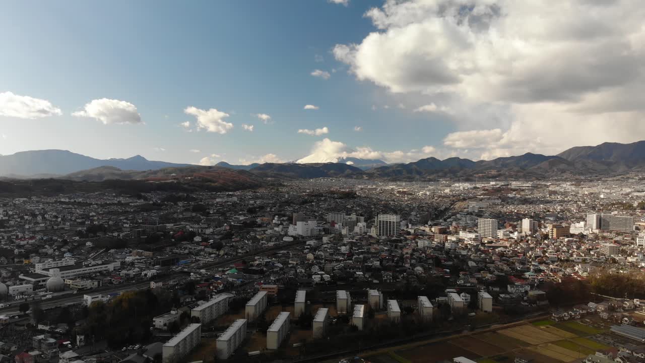 Stunning Scenery Of Wide Town Of Fujiyoshida And The Snowy Mount Fuji With White Clouds On Top - Aerial Drone Shot