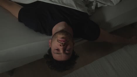 young bearded man lying on his bed staring at the ceiling pensively unable to sleep