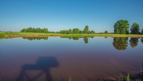 timelapse shot of cloud movement over pristine lake along rural landscape throughout the day