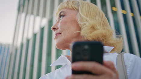 closeup grandmother looking mobile phone screen on street. mature lady message