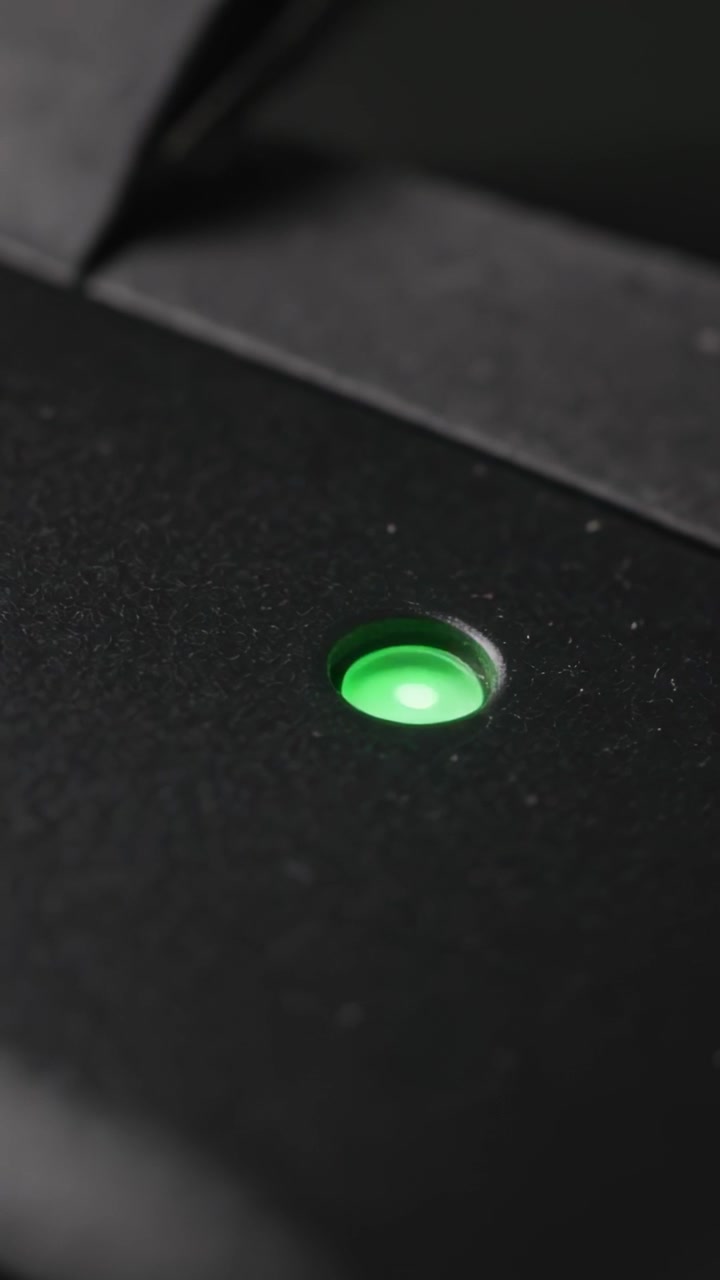 Vertical video: Shifting camera to reveal green LED on matte black housing, bezel clear, copy space