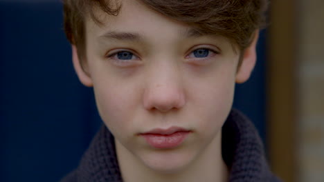 attractive sad boy with blue eyes looks into camera, closeup