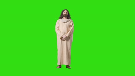 disparo de estudio de un hombre vestido con túnicas y sandalias con cabello largo y barba que representa la figura de jesucristo en la pantalla verde